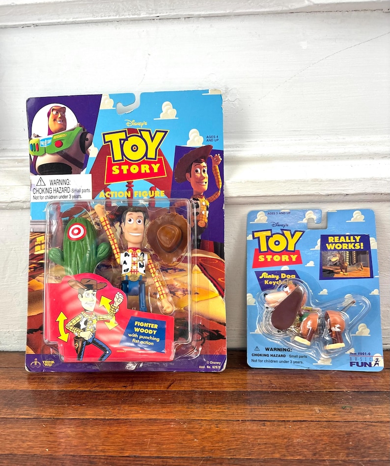 Peut inclure: Deux figurines Toy Story vintage dans leur emballage d'origine. L'une repr&eacute;sente Woody avec un poing perforant, l'autre un porte-cl&eacute;s Slinky Dog. L'emballage comprend le logo Disney Toy Story et des &eacute;tiquettes d'avertissement.