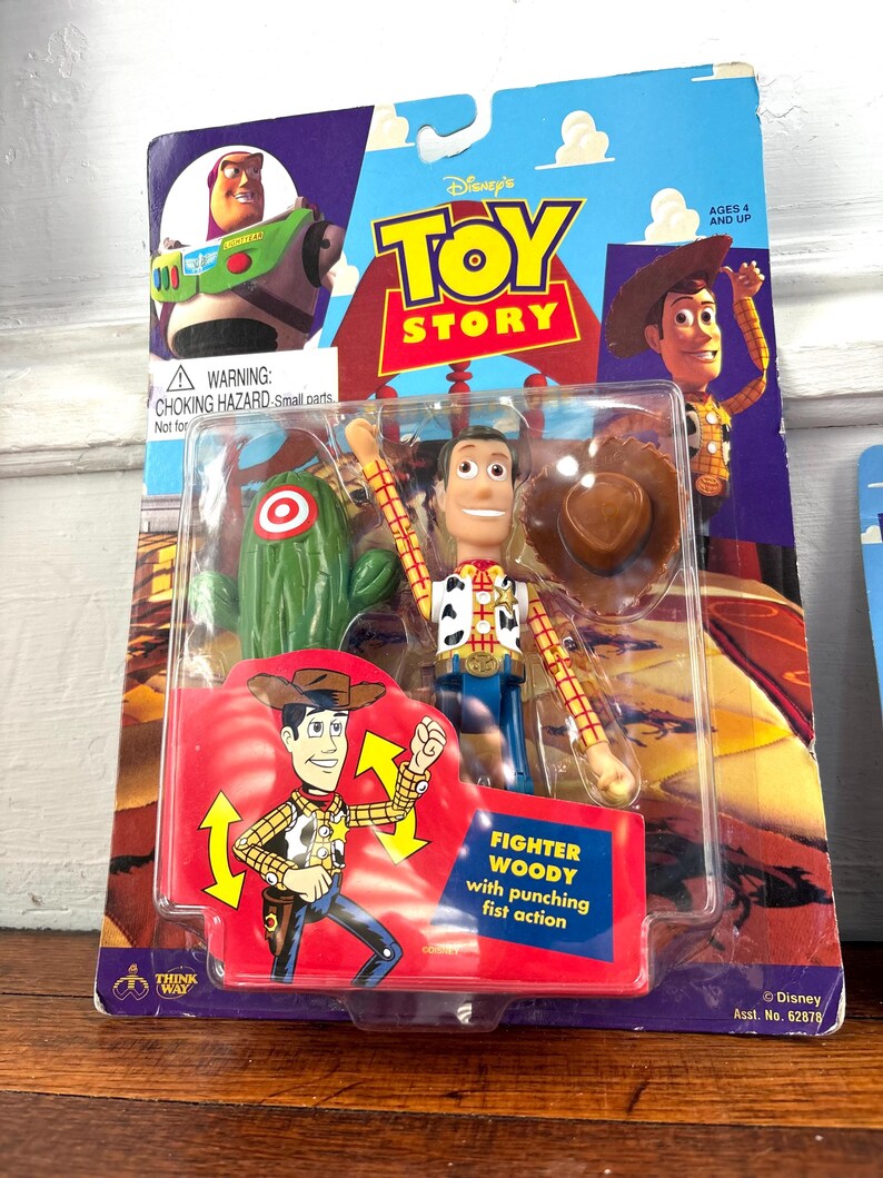 Peut inclure: Figurine articul&eacute;e Woody de Toy Story dans son emballage d'origine. L'emballage pr&eacute;sente des images de Woody, Buzz l'&Eacute;clair et un cactus. La figurine est dans un bo&icirc;tier en plastique transparent, avec l'inscription "Fighter Woody".