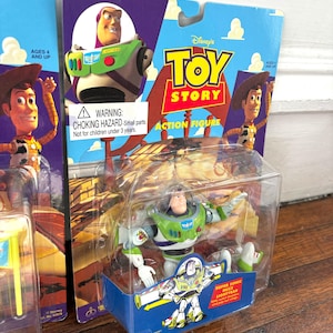 Może przedstawiać: Figurka Buzz Lightyear z Toy Story Disneya, zapakowana w przezroczystą plastikową obudowę. Opakowanie zawiera logo Toy Story, wizerunek Buzza Lightyeara oraz napis "ACTION FIGURE". Figurka jest zielona, biała i fioletowa.