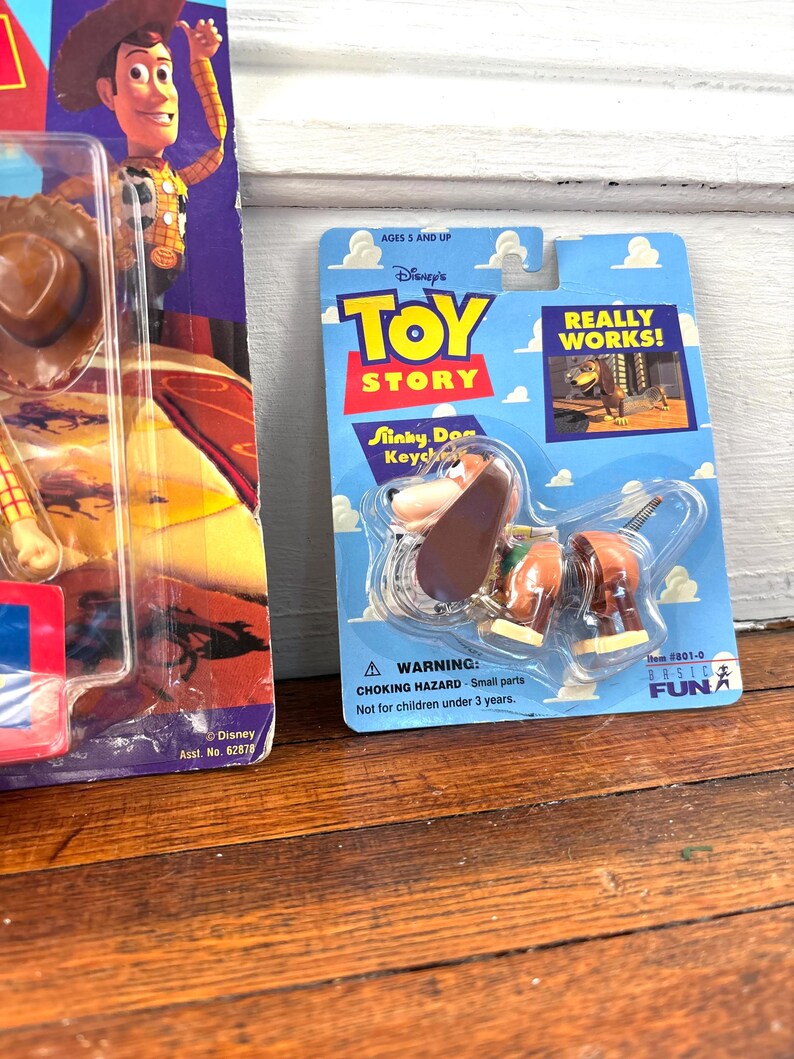 Peut inclure: Un porte-cl&eacute;s Slinky Dog emball&eacute; du film Disney Toy Story. L'emballage bleu et jaune pr&eacute;sente le logo Toy Story et les mots "REALLY WORKS!". L'emballage comprend &eacute;galement un avertissement de risque d'&eacute;touffement.