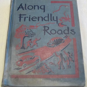 May include: A vintage book cover with a blue background and red border. The title is "Along Friendly Roads" in black lettering. The cover features a black and white illustration of a road with cars, trees, and people.