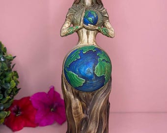 Könnte beinhalten: Detaillierte Statue einer Frau, die einen Globus hält. Die Statue zeigt eine Frau mit goldener Krone und fließendem Haar, die einen blau-grünen Globus hält. Der Sockel der Statue ist als Baumstamm gestaltet, mit rosa Hintergrund.