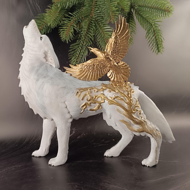 May include: A white wolf figurine with a gold eagle perched on its back. The wolf is in a howling pose, and the eagle has outstretched wings. Gold accents adorn the wolf's body, and the figurine is set against a dark background.