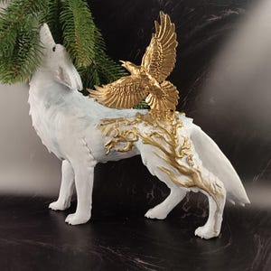 May include: A white wolf figurine with a gold eagle perched on its back. The wolf is howling, and gold-colored tree-like designs adorn its body. The eagle has outstretched wings. The figurine is a decorative item.