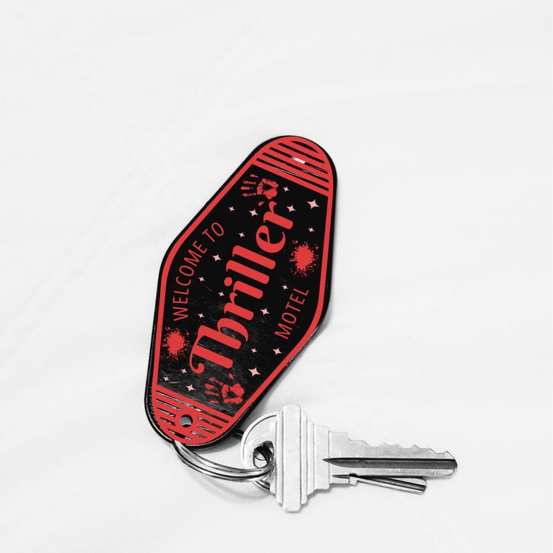 May include: A black and red motel key tag with the words "Thriller Motel" and "Welcome to" printed on it. The key tag has a key ring attached to it, and a silver key is connected to the ring. The key tag has a retro design with star and handprint graphics.