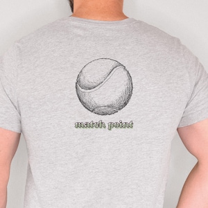 Könnte beinhalten: Hellgraues T-Shirt mit einer detaillierten Skizze eines Tennisballs auf dem Rücken. Unter dem Tennisball steht der Text "match point" in grüner Schrift. Das Shirt ist aus weichem Material.