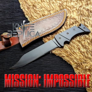May include: A black knife with a serrated edge and a curved blade, next to a brown leather sheath. The text "MISSION: IMPOSSIBLE" is displayed in red at the bottom. The text "KNIFE REPLICA" is displayed in the upper left corner.