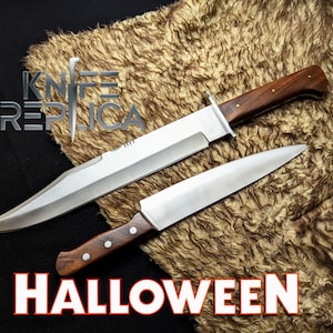 May include: Two knives with wooden handles and silver blades are displayed on a textured, brown surface. The larger knife has a wide blade and a guard. The words "KNIFE REPLICA" and "HALLOWEEN" are visible in the image.