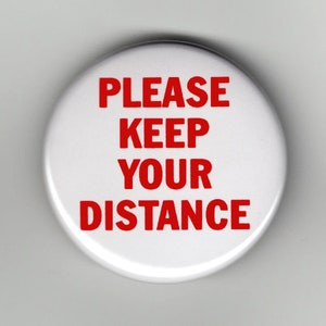 May include: White round button with red text that reads "PLEASE KEEP YOUR DISTANCE".
