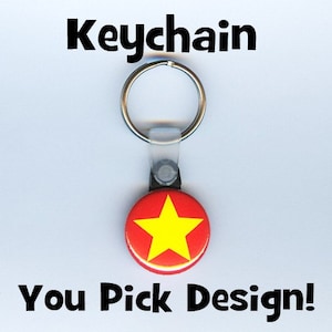 May include: A red and yellow star keychain with a silver ring. You Pick Design! is written below the star.