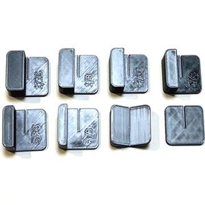 Puede incluir: Ocho objetos grises rectangulares impresos en 3D con una ranura en forma de U y texto que indica medidas. Los objetos están dispuestos sobre una superficie blanca. Las medidas son 1/16, 1/8, 3/16 y 1/4.