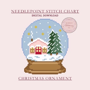 Op de afbeelding: Een digitaal kruissteekpatroon voor een kerstversiering. Het ontwerp toont een gepixelde sneeuwbol met een roze huis, een groene boom en vallende sneeuw. De tekst luidt "Needlepoint Stitch Chart" en "Christmas Ornament".