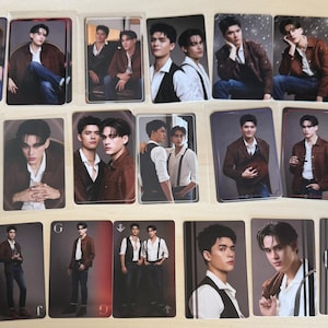 Puede incluir: Colecci&oacute;n de cromos con retratos de una persona en varias poses. Las tarjetas tienen un acabado brillante y muestran a la persona con chaquetas, chalecos y camisas. Las tarjetas est&aacute;n dispuestas sobre una superficie clara, probablemente para coleccionar.
