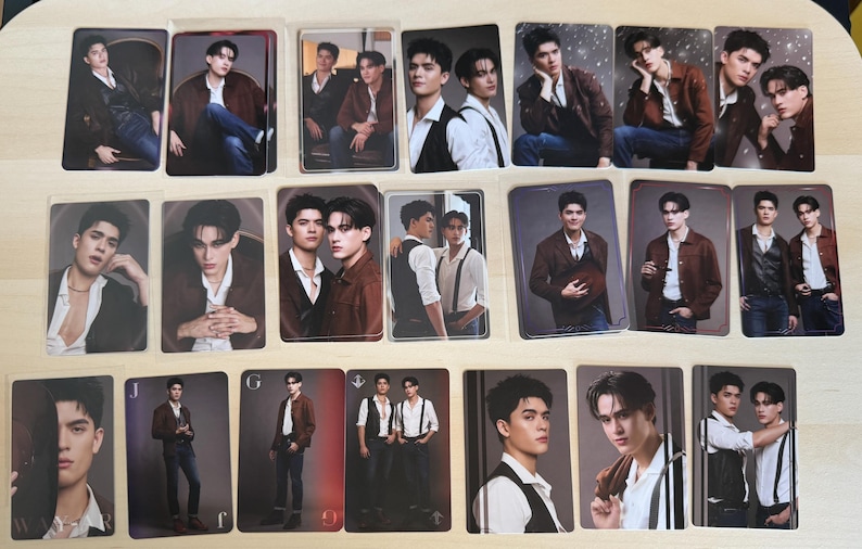 Puede incluir: Colecci&oacute;n de cromos con retratos de una persona en varias poses. Las tarjetas tienen un acabado brillante y muestran a la persona con chaquetas, chalecos y camisas. Las tarjetas est&aacute;n dispuestas sobre una superficie clara, probablemente para coleccionar.