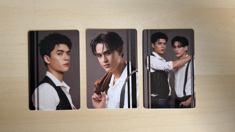 Puede incluir: Tres tarjetas rectangulares con retratos de hombres j&oacute;venes. Los hombres visten camisas blancas, chalecos y tirantes. Un hombre sostiene una chaqueta marr&oacute;n sobre su hombro. Las tarjetas est&aacute;n dispuestas sobre una superficie de madera clara.