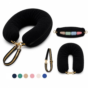 May include: Black travel neck pillow with a zip and gold-coloured hardware. Includes a matching strap with gold and black stripes. The image also shows a small pouch with colourful items inside and a second neck pillow.