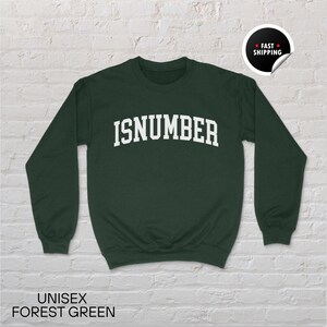May include: A forest green unisex sweatshirt with the word "ISNUMBER" in white block letters across the chest. The sweatshirt has long sleeves and a crew neck. The words "UNISEX FOREST GREEN" are printed at the bottom of the image.