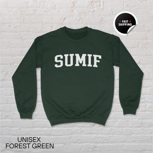 Peut inclure: Sweat-shirt unisexe vert forêt avec le mot "SUMIF" en lettres blanches sur la poitrine. Le sweat-shirt a des manches longues et un col rond. Le texte "UNISEX FOREST GREEN" est imprimé en bas de l'image.