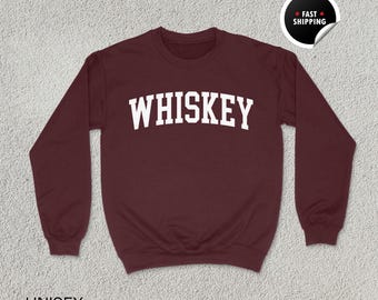 Può includere: Una felpa color granata con la scritta "WHISKEY" stampata in bianco sul davanti.