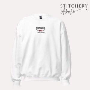 May include: White crewneck sweatshirt with the word "MONTREAL" in black, a red and white Canadian flag graphic, and the text "EST. 1642" and "LA VILLE AUX CENT CLOCHERS" in black. The brand name "STITCHERY Adventure" is in black script.