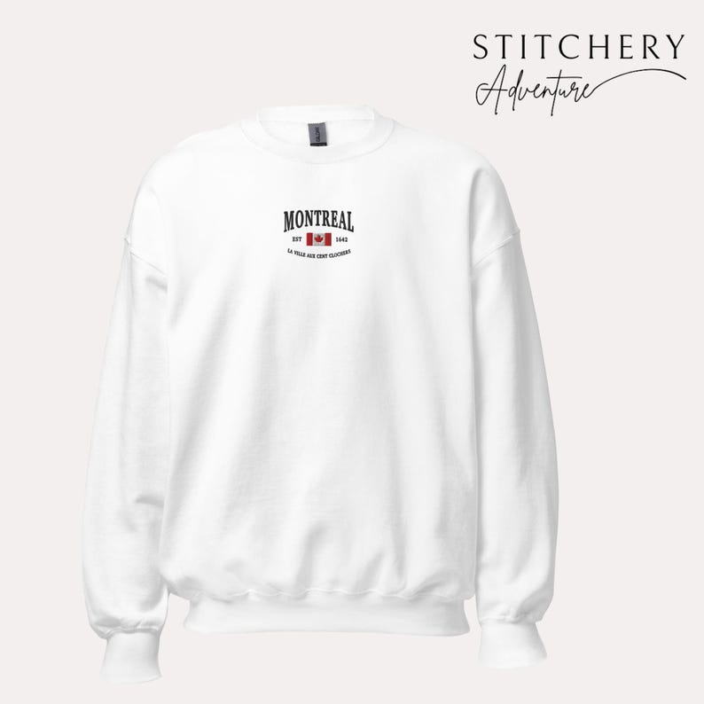 May include: White crewneck sweatshirt with the word "MONTREAL" in black, a red and white Canadian flag graphic, and the text "EST. 1642" and "LA VILLE AUX CENT CLOCHERS" in black. The brand name "STITCHERY Adventure" is in black script.