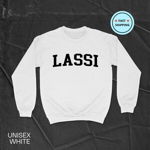 Könnte beinhalten: Weißes Sweatshirt mit dem Wort "LASSI" in fetten schwarzen Buchstaben auf der Brust. Das Sweatshirt hat lange Ärmel und einen Rundhalsausschnitt. Die Worte "UNISEX WHITE" sind unten aufgedruckt. Ein "FAST SHIPPING"-Aufkleber befindet sich oben rechts.