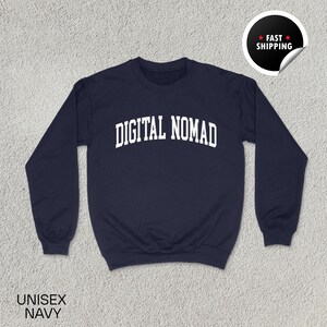 May include: Navy blue unisex sweatshirt with the text "DIGITAL NOMAD" in white, arched lettering. The sweatshirt has a crew neck and long sleeves. The words "UNISEX NAVY" are printed at the bottom left. A "FAST SHIPPING" sticker is in the upper right corner.