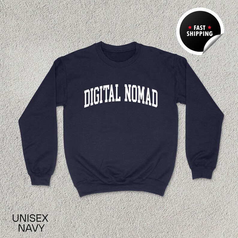 May include: Navy blue unisex sweatshirt with the text "DIGITAL NOMAD" in white, arched lettering. The sweatshirt has a crew neck and long sleeves. The words "UNISEX NAVY" are printed at the bottom left. A "FAST SHIPPING" sticker is in the upper right corner.