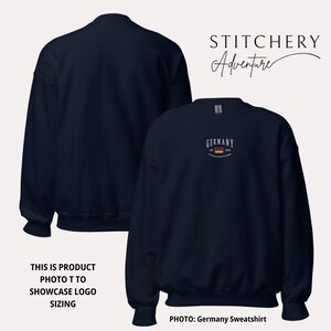 May include: Navy blue sweatshirt with the word "GERMANY" in white above a small German flag graphic. The sweatshirt has the text "EST. 1996" and "THE UNITED STATES OF AMERICA" below the flag. The image also includes the text "STITCHERY Adventure".