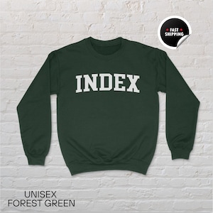 May include: Forest green unisex sweatshirt with the word "INDEX" in white block letters across the chest. The sweatshirt has long sleeves and a crew neck. The words "UNISEX FOREST GREEN" are printed at the bottom of the image.