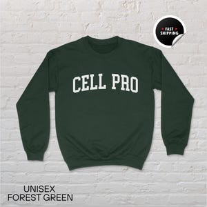 May include: A forest green unisex sweatshirt with the text "CELL PRO" in white block letters. The sweatshirt has long sleeves and a crew neck. The words "UNISEX FOREST GREEN" are printed at the bottom of the image.