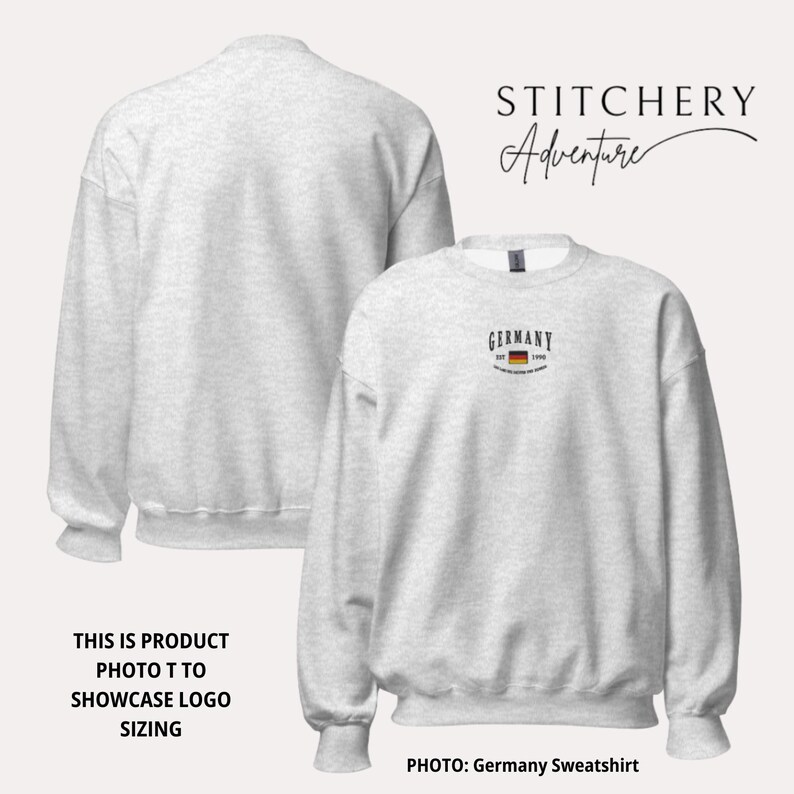 May include: Light gray sweatshirt with the word "GERMANY" and a small German flag graphic. The sweatshirt has a crew neck and long sleeves. The text "STITCHERY Adventure" is in the upper right corner. The photo showcases logo sizing.