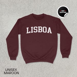 May include: Maroon sweatshirt with the word "LISBOA" printed in white on the front.