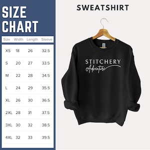 May include: Black sweatshirt with the text "STITCHERY Adventure" in white script. A size chart is displayed on the left, showing measurements in inches for width, length, and sleeve length, ranging from XS to 4XL.