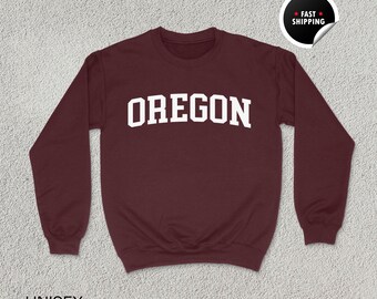 May include: A maroon sweatshirt with the word "OREGON" printed in white on the front. The sweatshirt is a unisex size.