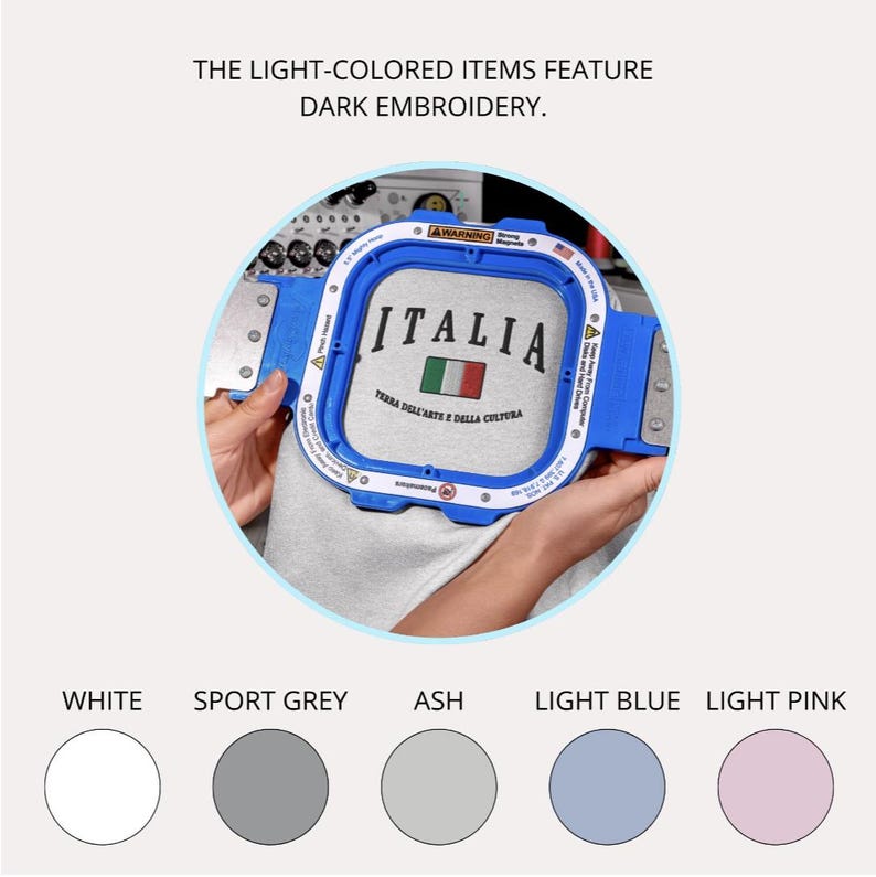 Puede incluir: Un bastidor de bordado azul que sostiene una tela gris con la palabra "ITALIA" bordada en negro, junto con la bandera italiana. El texto "TERRA DELL'ARTE E DALLA CULTURA" tambi&eacute;n est&aacute; bordado. La imagen tambi&eacute;n muestra muestras de color: blanco, gris deportivo, ceniza, azul claro y rosa claro.