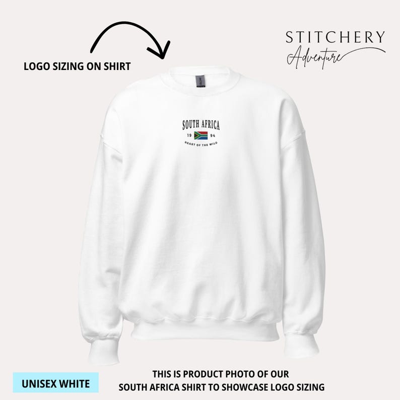 May include: White unisex sweatshirt with the text "SOUTH AFRICA" and a small flag graphic. The sweatshirt also has the text "HEART OF THE WILD" and the numbers "19" and "94". The sweatshirt is a product photo to showcase logo sizing.