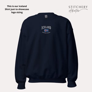 Puede incluir: Sudadera azul marino con la palabra "ICELAND" bordada en blanco, junto con la bandera islandesa. El texto "northern europe" est&aacute; debajo de la bandera. La sudadera tambi&eacute;n tiene el texto "This is our Iceland Shirt just to showcase logo sizing".