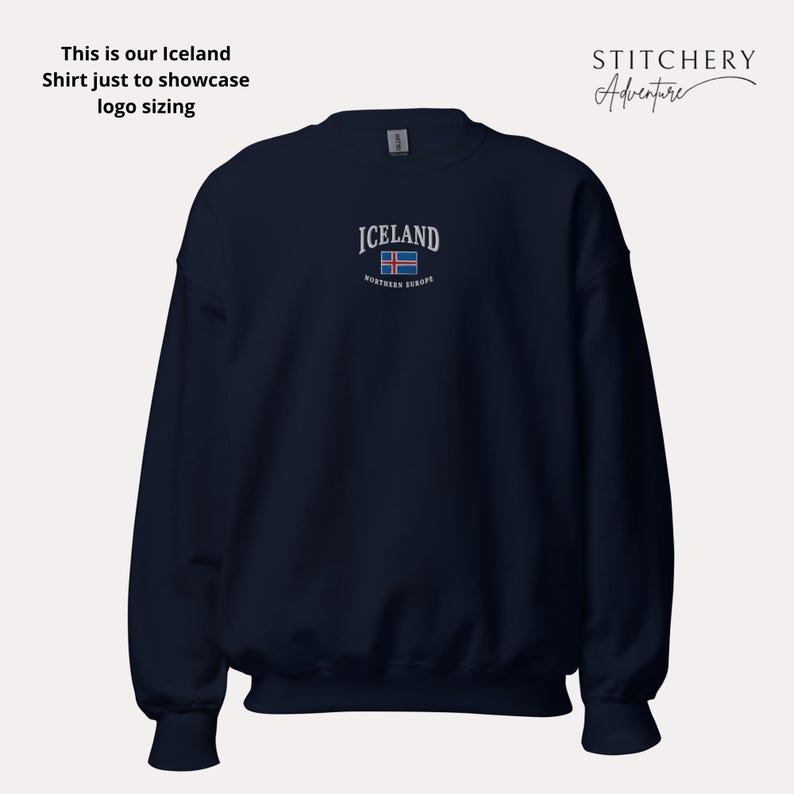Puede incluir: Sudadera azul marino con la palabra "ICELAND" bordada en blanco, junto con la bandera islandesa. El texto "northern europe" est&aacute; debajo de la bandera. La sudadera tambi&eacute;n tiene el texto "This is our Iceland Shirt just to showcase logo sizing".