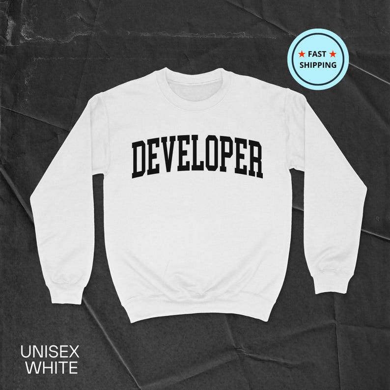 May include: White unisex sweatshirt with the word "DEVELOPER" printed in bold black letters across the chest. The sweatshirt has long sleeves and a crew neck. The words "UNISEX WHITE" are printed at the bottom.