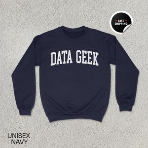 May include: Navy blue unisex sweatshirt with the text "DATA GEEK" in white block letters. The sweatshirt has a crew neck and long sleeves. The words "UNISEX NAVY" are printed at the bottom left.