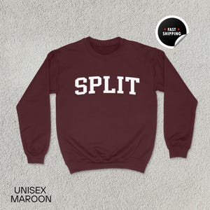 Könnte beinhalten: Burgunderfarbenes Unisex-Sweatshirt mit dem Wort "SPLIT" in großen weißen Blockbuchstaben auf der Brust. Das Sweatshirt hat lange Ärmel und einen Rundhalsausschnitt. Der Text "UNISEX MAROON" ist unten aufgedruckt.