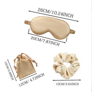 May include: A set of three gold-coloured satin sleep accessories: a sleep mask, a hair scrunchie, and a small pouch. The sleep mask measures 26 cm by 20 cm, the hair scrunchie measures 10 cm in diameter, and the pouch measures 15 cm by 12 cm.