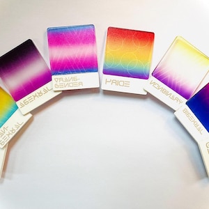 Peut inclure: Un ensemble de huit drapeaux de fierté carrés avec différentes couleurs et dégradés. Chaque drapeau a une étiquette blanche avec du texte identifiant la signification du drapeau, y compris "Lesbienne", "Pansexuel", "Transgenre", "Fierté", "Non-binaire", "Bisexuel", "Gay" et "Asexuel".