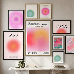 May include: A gallery wall arrangement featuring nine framed posters with aura gradient designs, including text such as Charming Courageous Loyal Scorpio, Mind, Divine Energy, Abundance, and Balance, displayed in black and gold frames on a wall.