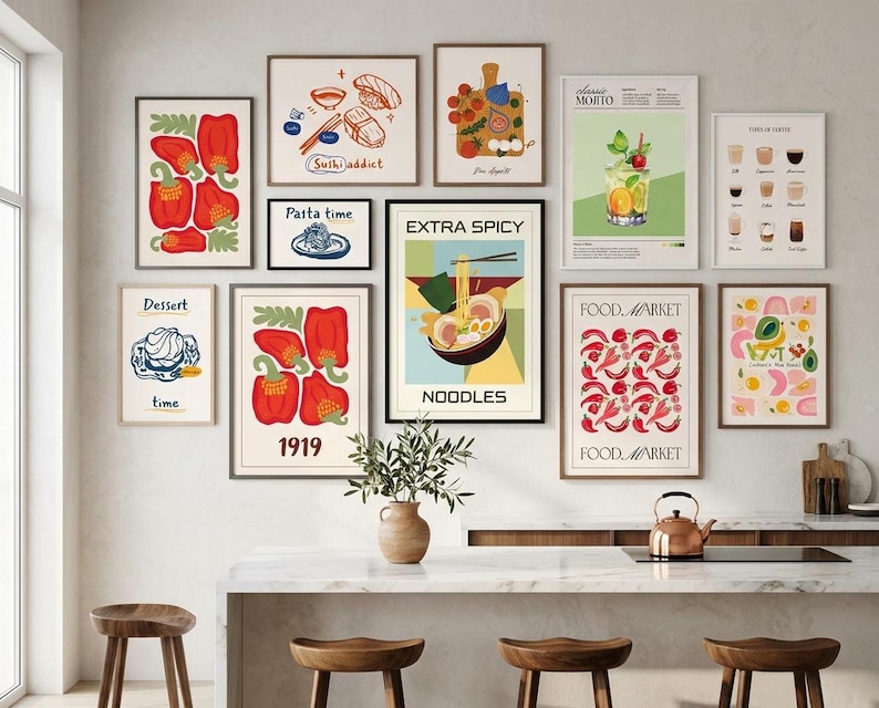 A gallery wall arrangement of ten food prints featuring ramen, sushi, peppers, and cocktails above a kitchen island with bar stools.