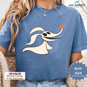 Puede incluir: Camiseta azul vaquero de color c&oacute;modo con un perro fantasma de dibujos animados con una nariz de calabaza. La camiseta tiene el texto "JW APRINT" y "BLUE JEAN Comfort Color". La imagen tambi&eacute;n incluye el texto "156 COLOR Mockup Catalog in the 2nd image".