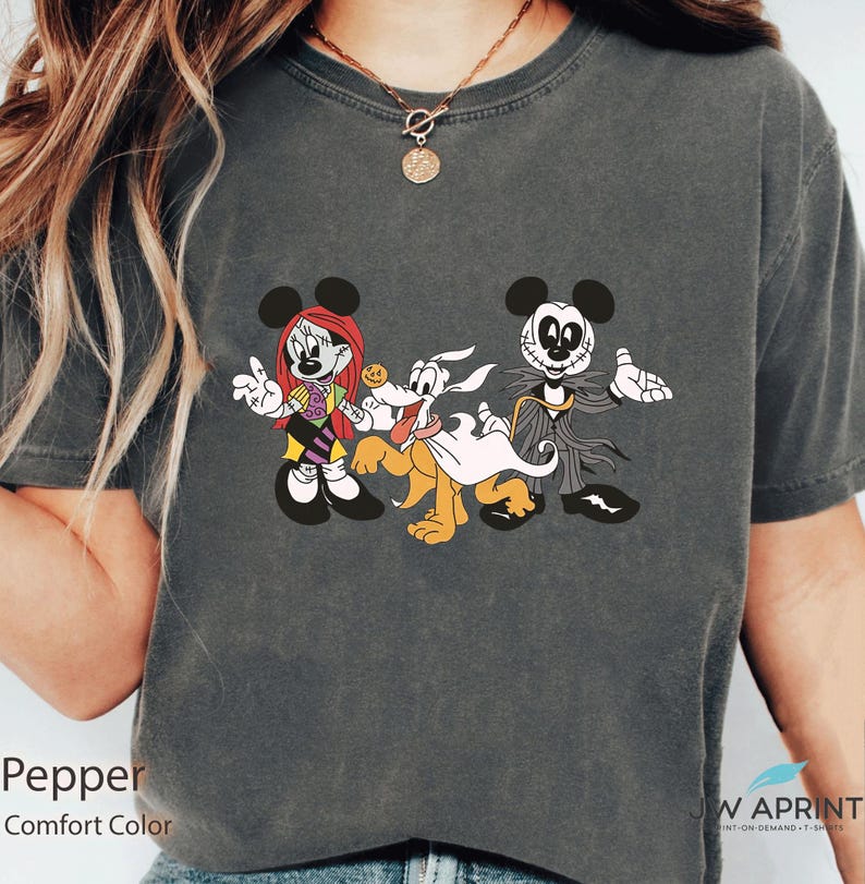 Puede incluir: Camiseta gris oscuro con un dise&ntilde;o de dibujos animados con tem&aacute;tica de Halloween. El dise&ntilde;o incluye un personaje de rat&oacute;n femenino con pelo rojo, un perro y un personaje de rat&oacute;n masculino con traje. La camiseta est&aacute; etiquetada como "Pepper" y "Comfort Color".