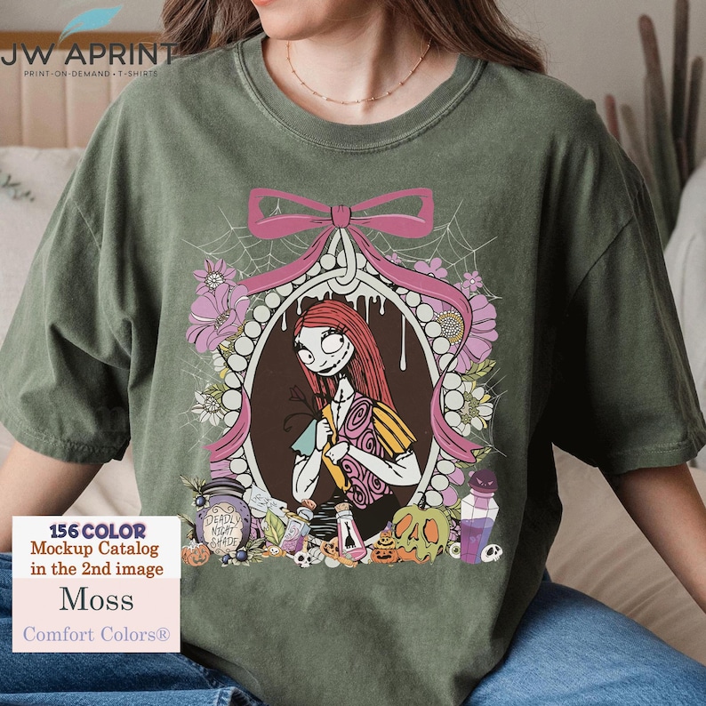 May include: A moss green t-shirt featuring a framed illustration of a character with red hair and a patchwork dress, surrounded by flowers and a pink bow. The shirt includes text that reads "JW APRINT" and "Comfort Colors&reg;". Additional text includes "156 COLOR Mockup Catalog in the 2nd image".
