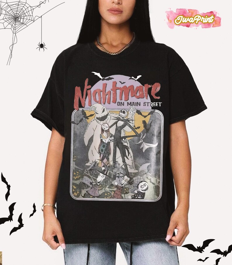 May include: Black t-shirt featuring a graphic from "The Nightmare Before Christmas." The design includes Jack Skellington, Sally, and Oogie Boogie, with the text "Nightmare on Main Street." Bats and a spiderweb are in the background.